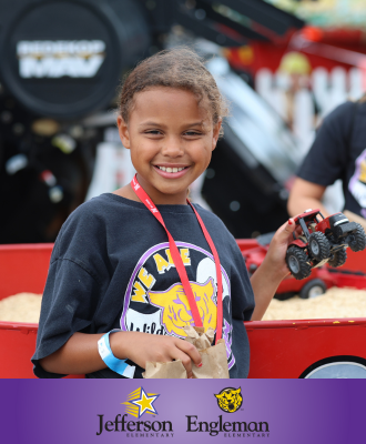  Smiling student at the State Fair holding a toy tractor.